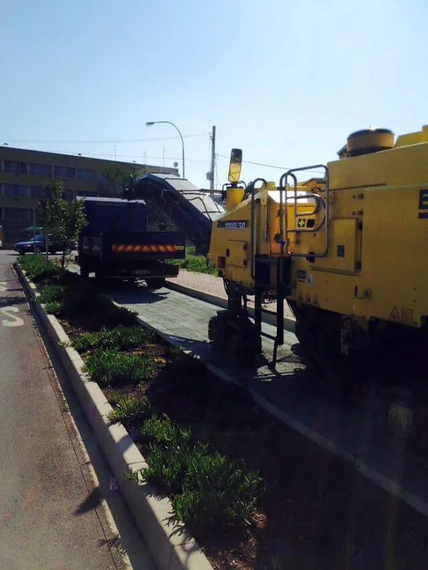 Milling machine stripping a road beside a landscaped median